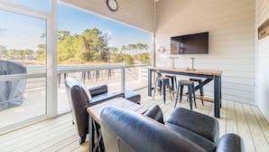 An outdoor deck with a wooden table and chairs, a TV mounted on the wall, and a view of trees and sky. - The Turn at Kilmarlic - Kilmarlic Golf Club, Sits on 10th Tee, Water Park Nearby, YR Flex Stays (Powells Point)
