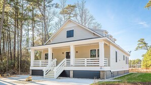 A two-story house with a covered porch and a staircase leading to the entrance. - The Turn at Kilmarlic - Kilmarlic Golf Club, Sits on 10th Tee, Water Park Nearby, YR Flex Stays (Powells Point)