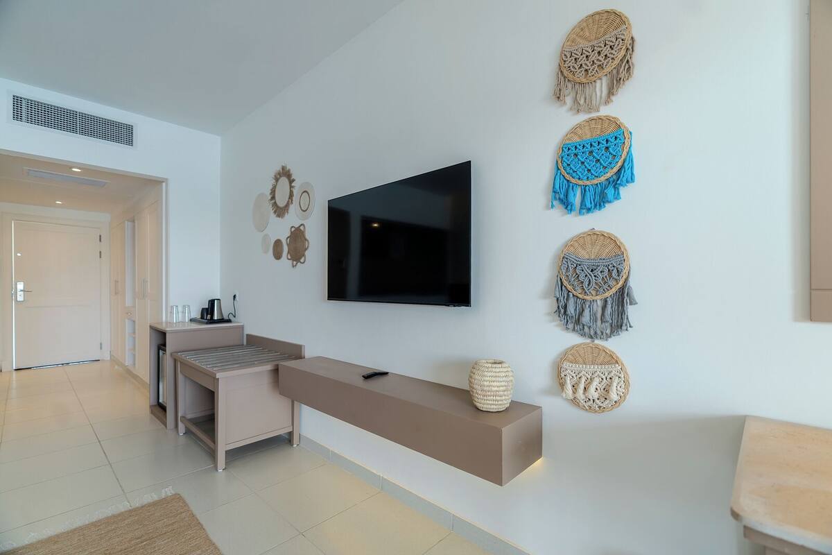 Uma sala de estar moderna com uma TV de tela plana, um sofá, uma mesa de centro e painéis decorativos na parede.