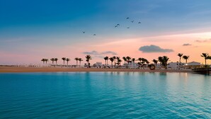 A coastal resort with a beachfront, palm trees, and a clear sky. - Casa Blue Resort (Marsa Alam)