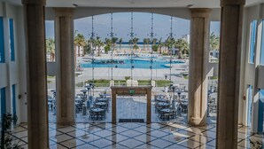 A view of a pool area with a tiled floor, surrounded by palm trees and a clear sky. - Casa Blue Resort (Marsa Alam)