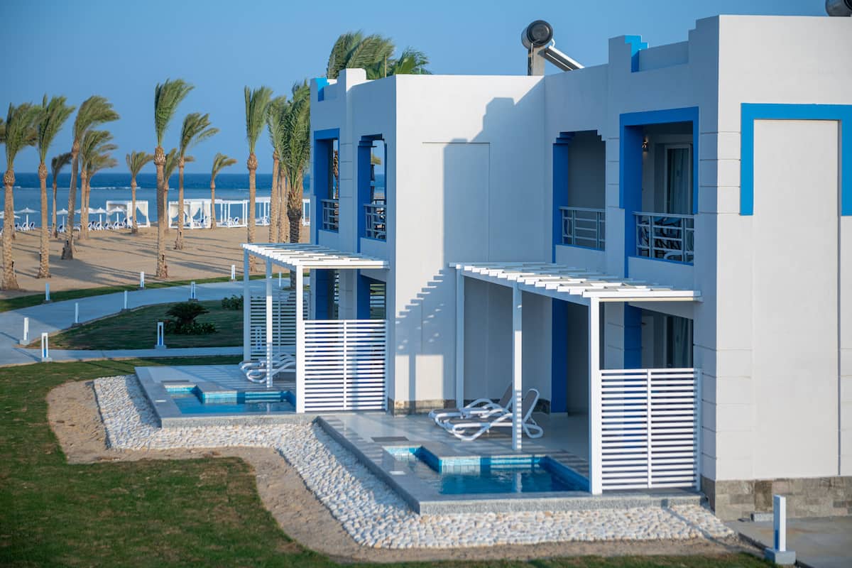 Um edifício moderno com área de piscina, incluindo espreguiçadeiras e uma piscina pequena.