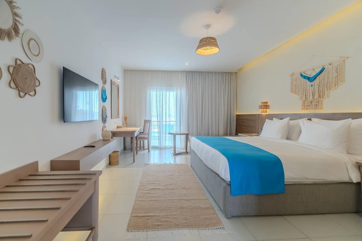 Quarto de hotel moderno com cama, escrivaninha e televisão.