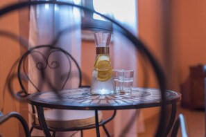 A clear glass pitcher with a lemon slice on a metal table. - Lemon Tree Boutique Guesthouse (Todi)