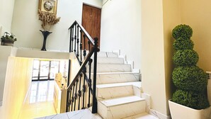 Una escalera con escalones de mármol blanco, una puerta de madera y una planta en maceta.