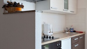 Een koffiezetapparaat/waterkoker, een koelkast, een oven, een kookplaat