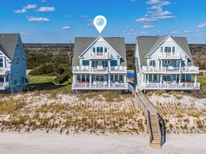 A beachfront property with a central house featuring a balcony and a deck.
