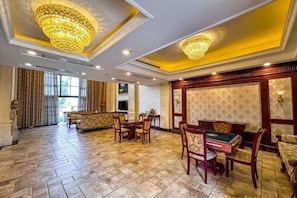 A spacious lobby with a high ceiling, ornate chandeliers, a billiards table, and comfortable seating areas. - Guangning Overseas Chinese Hotel (Guangning)