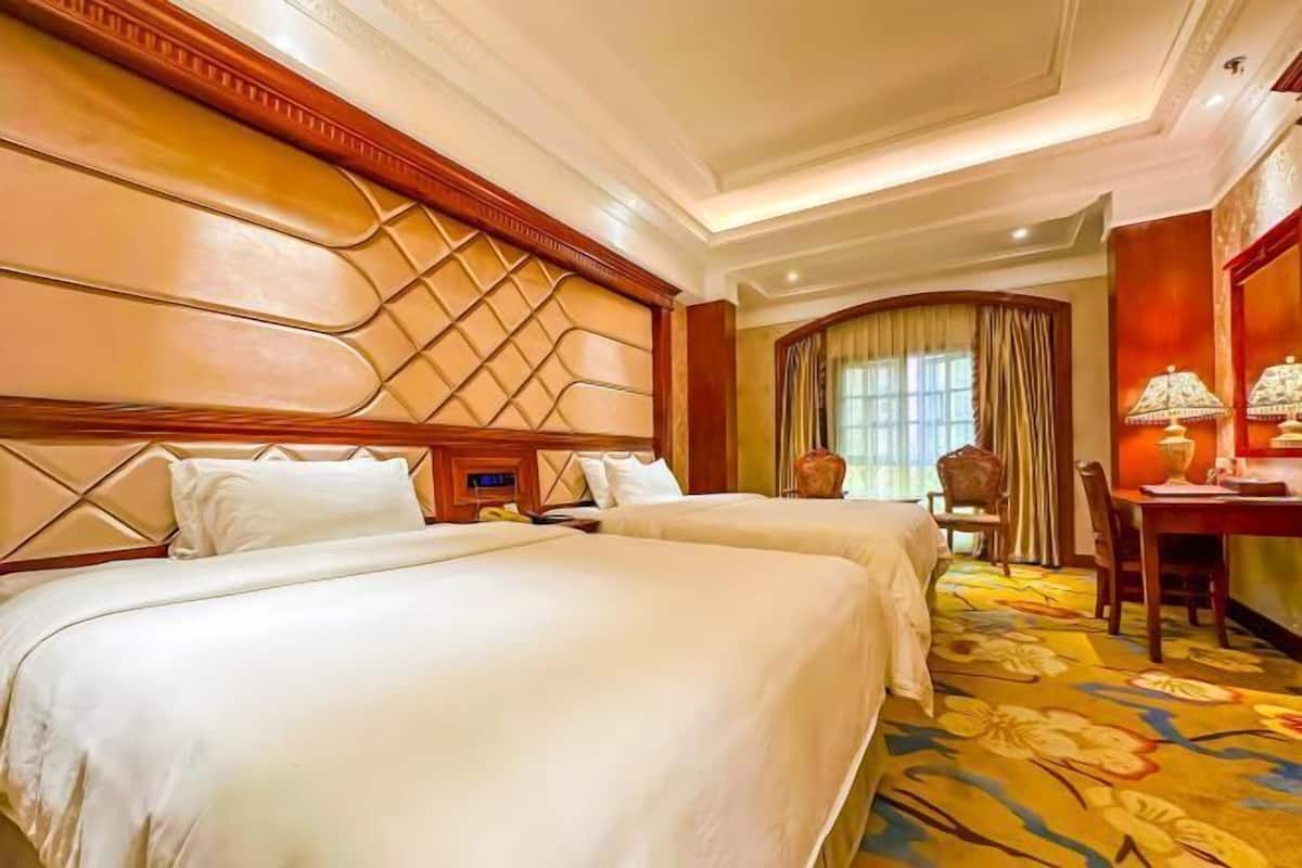 Une chambre d’hôtel avec deux lits, une table à manger et un lustre.