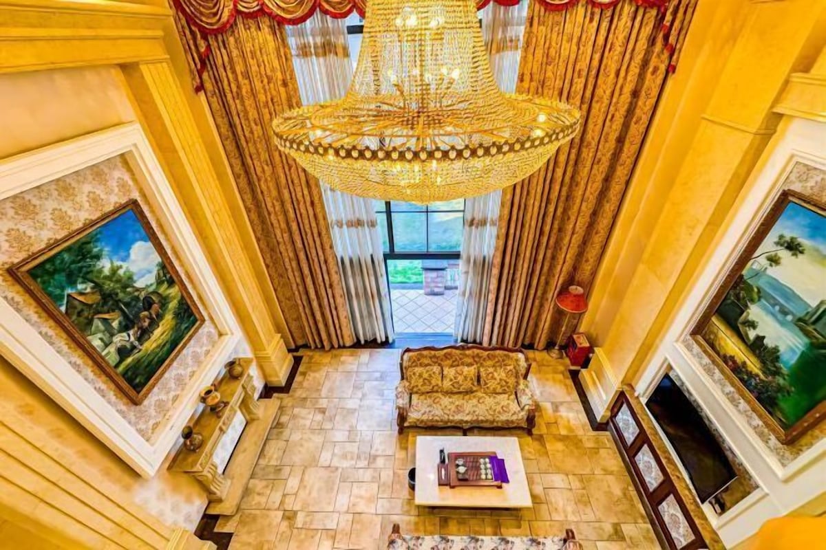 A grand lobby with a chandelier, a sofa, and paintings on the walls.