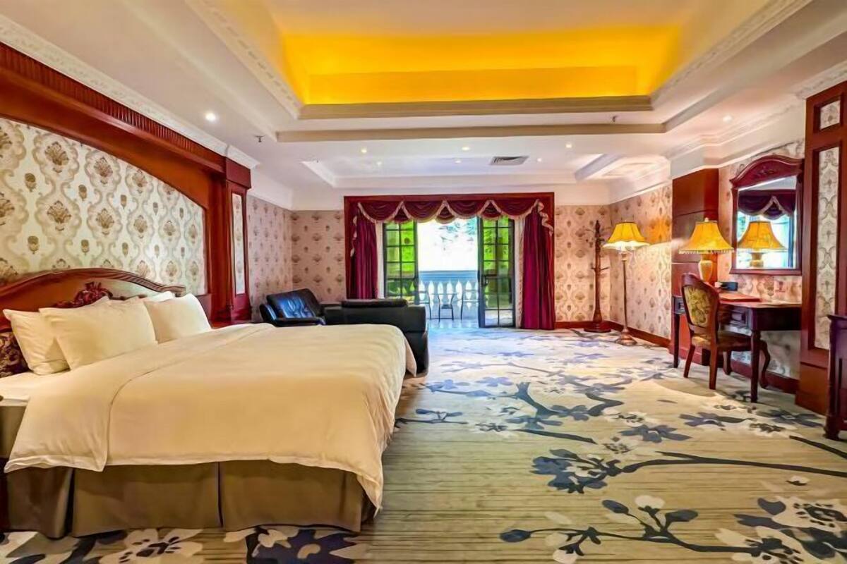 Une chambre d’hôtel avec un grand lit, un bureau, une chaise et une vue sur l’extérieur.