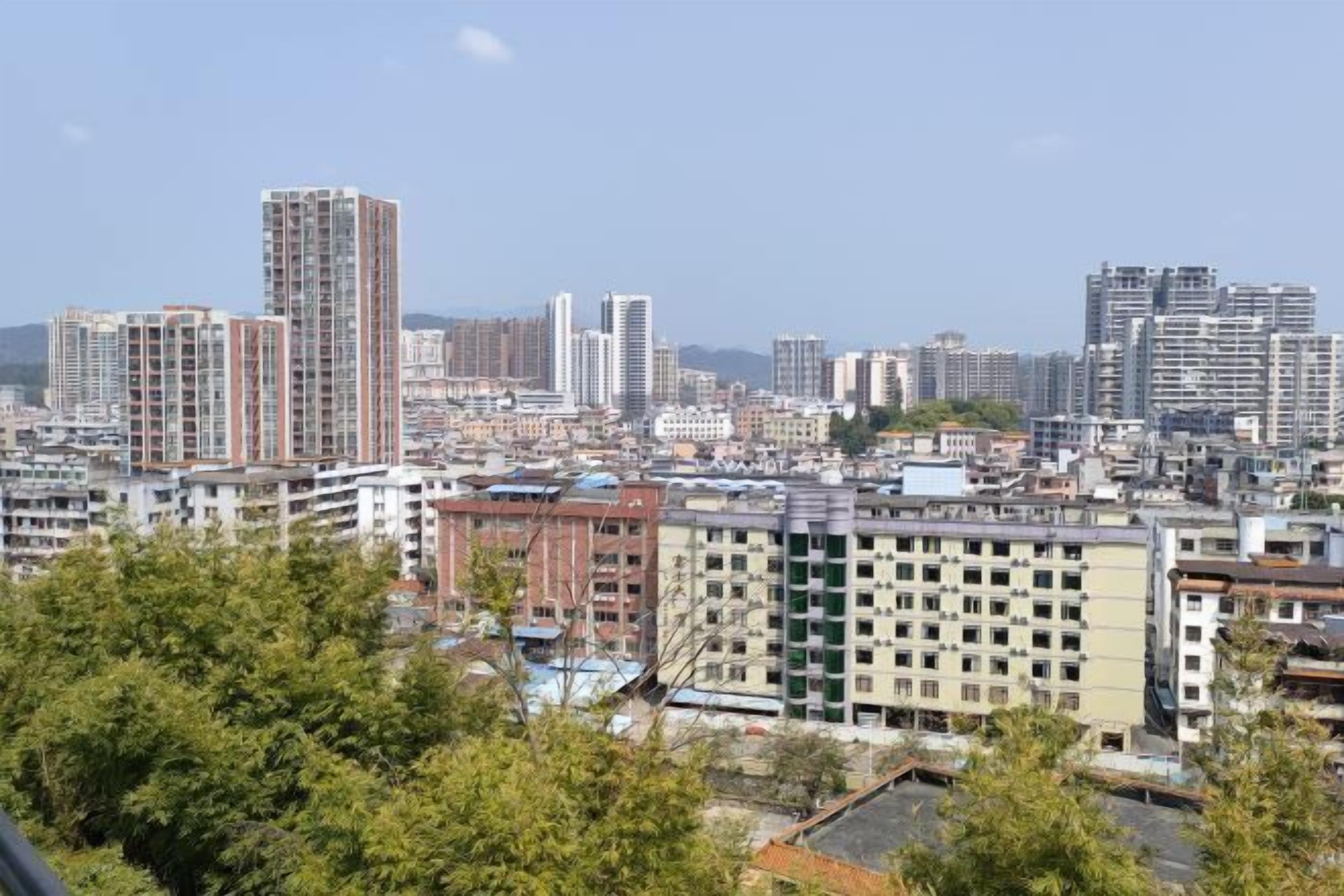 A cityscape with high-rise buildings, including a prominent tall building with a unique design.