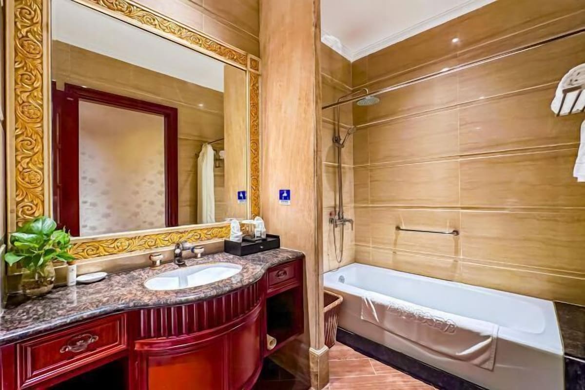 A bathroom with a marble vanity, a large mirror, a bathtub, and a shower area.