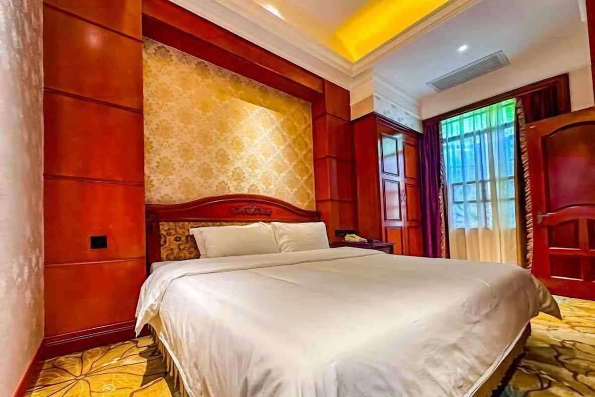 Une chambre d’hôtel avec un grand lit, une tête de lit en bois, un mur à motifs et une fenêtre avec des rideaux.