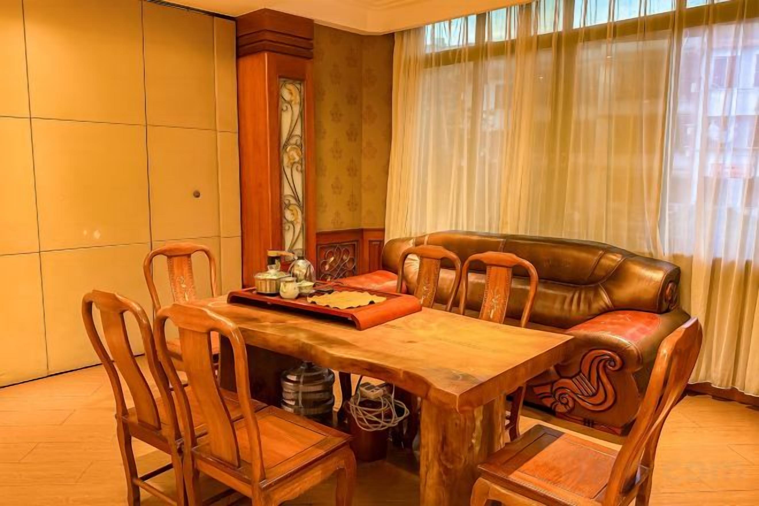 A dining area with a wooden table and chairs, a decorative tray, and a leather sofa.