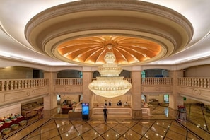 A spacious lobby with a grand chandelier, a reception desk, and a check-in counter. - Guangning Overseas Chinese Hotel (Guangning)