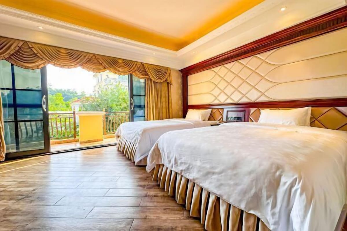 A hotel room with two beds, a large window with curtains, a balcony, and a modern interior design.