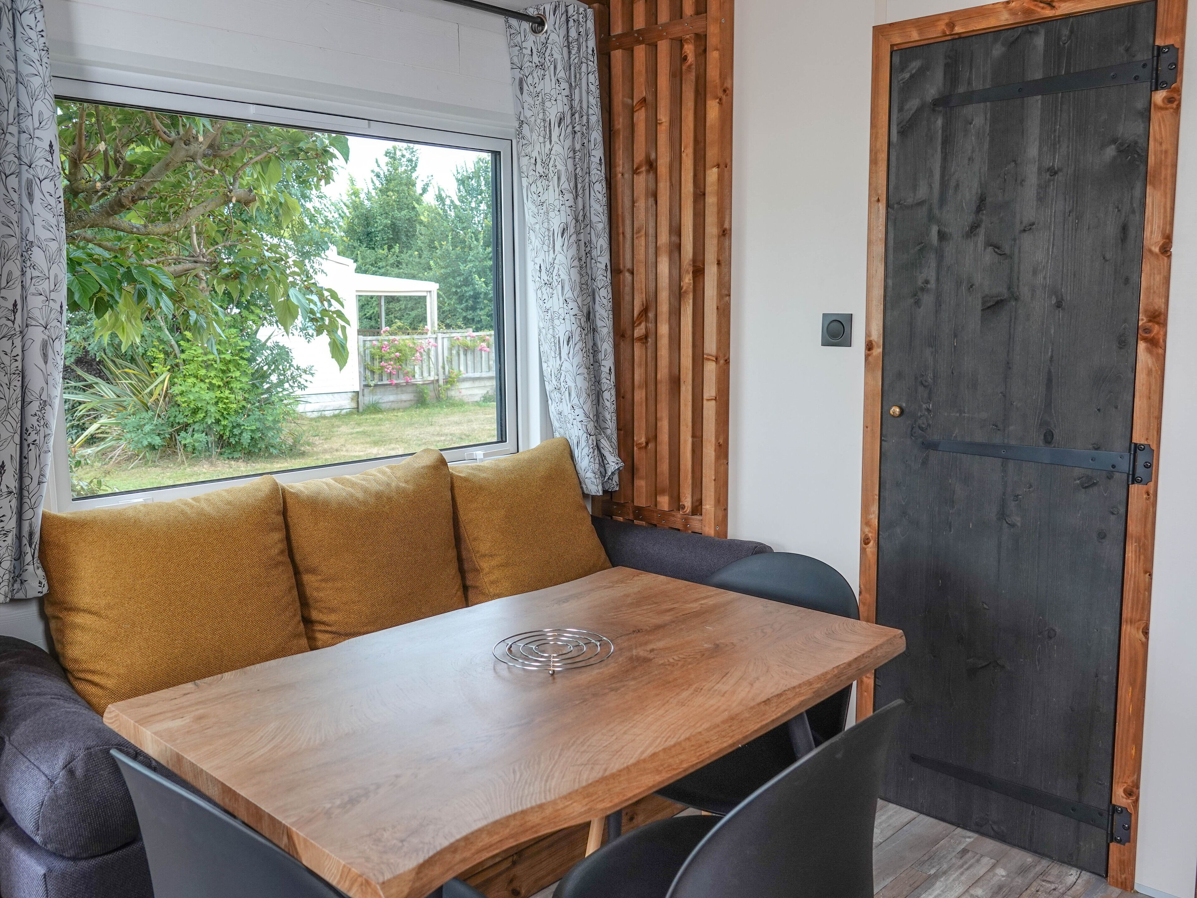 Una habitación acogedora con una mesa de madera, un banco acolchado y vistas al exterior.