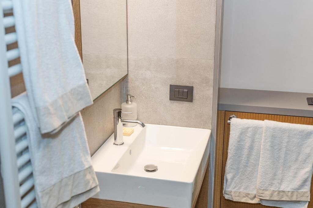 A bathroom with a white sink, a mirror, and a towel rack.