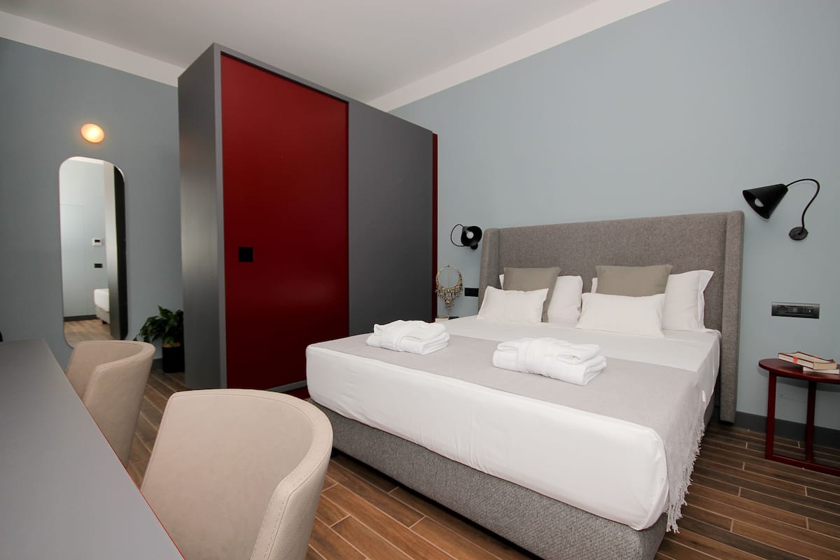 Ein modernes Hotelzimmer mit einem großen Bett, einem Schreibtisch und einem Sessel.