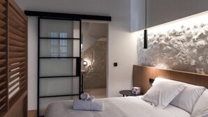 A modern hotel room with a bed, a wooden wardrobe, a sliding door, and a textured wall. - Houmi Orzán - Apt. Rosalia de Castro (A Coruña)