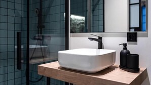 A modern bathroom with a glass shower enclosure, a white vessel sink, and a wooden countertop. - Houmi Orzán - Apt. Rosalia de Castro (A Coruña)