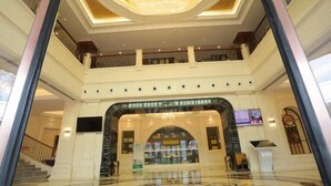 A spacious lobby with a grand chandelier, a central archway, and a high ceiling. - Ruipu Hotel (Daozhen)