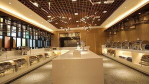 A modern hotel lobby with a central reception desk, a wooden ceiling with a grid pattern, and a display of chairs on the right side. - Ruipu Hotel (Daozhen)