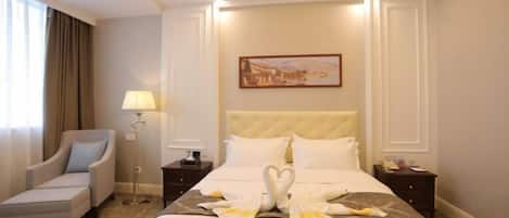 A hotel room with a large bed, a chair, a nightstand, a lamp, and a painting on the wall.