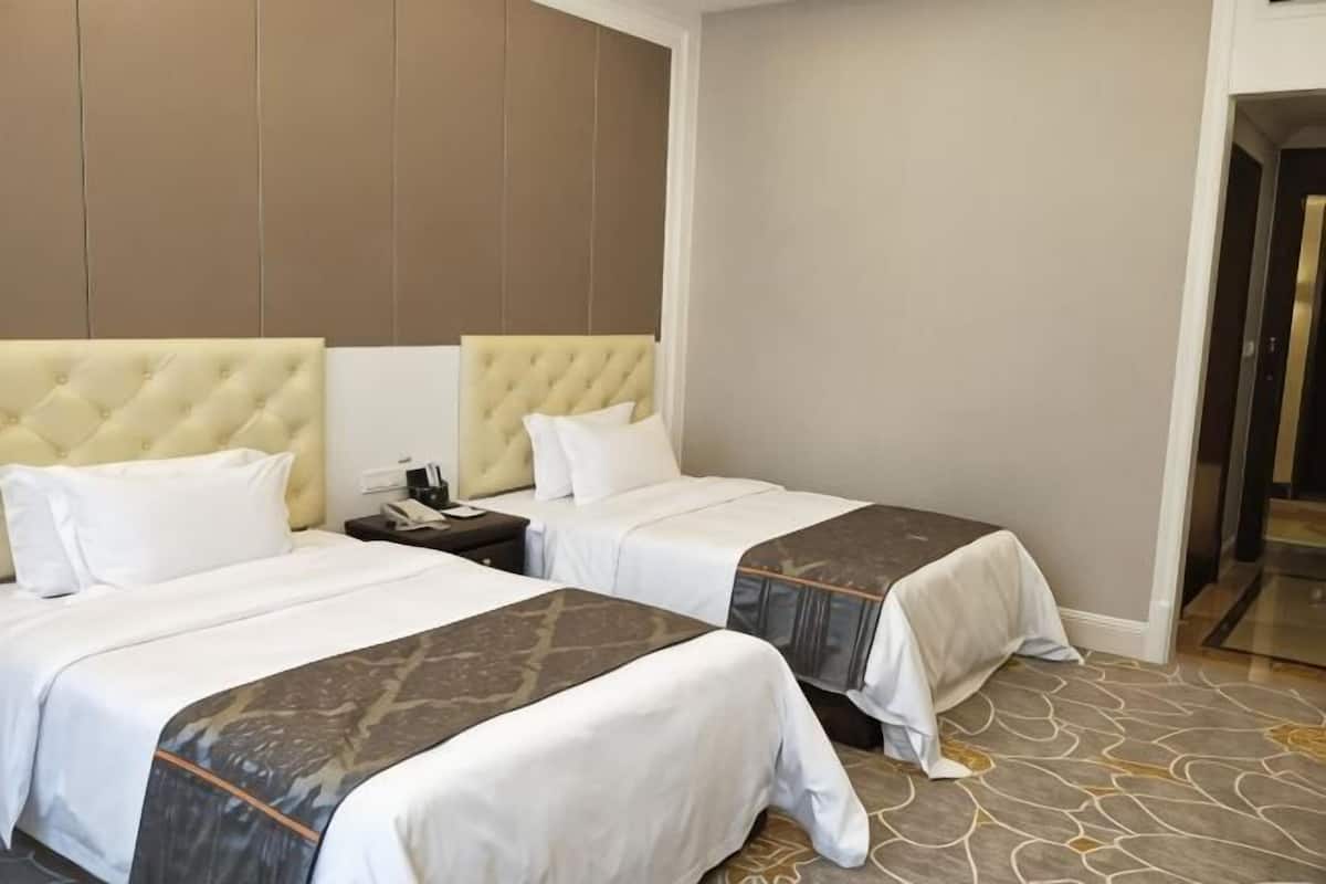 Habitació d'hotel amb dos llits, una tauleta de nit i un terra amb moqueta.