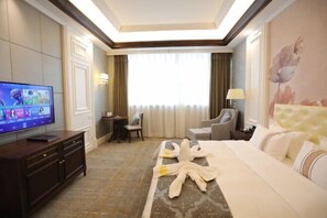 A hotel room with a television, a desk, a chair, a bed, and a window with curtains. - Ruipu Hotel (Daozhen)
