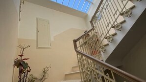 Un escalier avec une rampe en métal et une lucarne au-dessus.