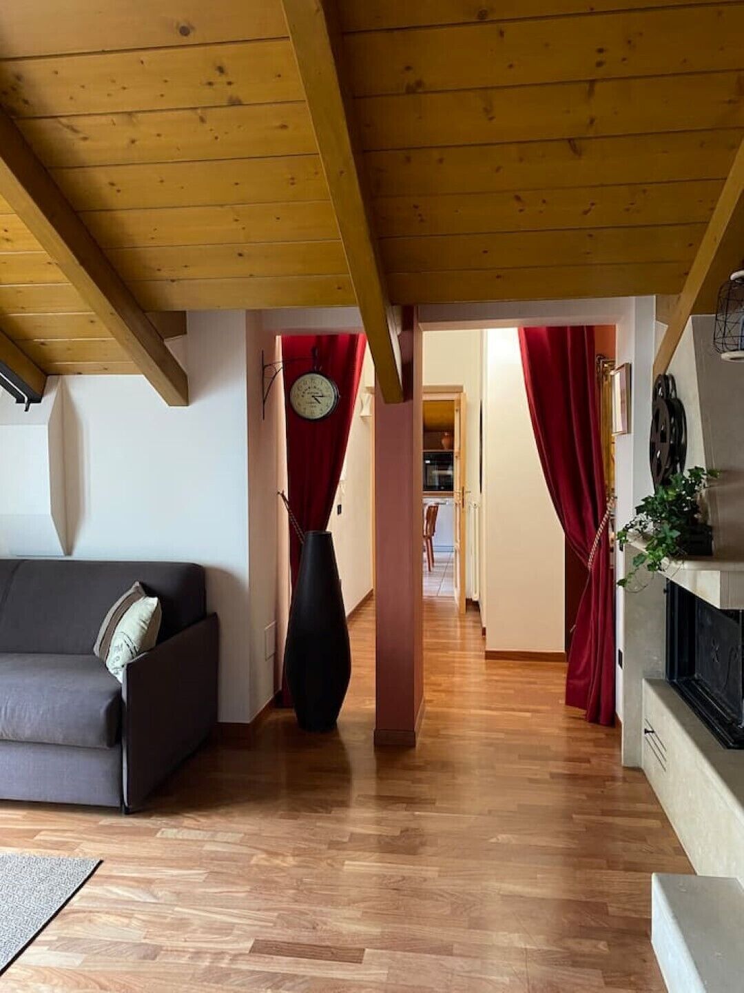 Un salon chaleureux avec un plafond en bois, un canapé, un grand vase et une cheminée.