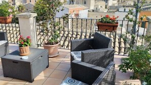 Un balcon agrémenté de meubles en osier, de plantes en pot et offrant une vue sur le paysage urbain.