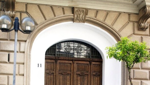 Une grande porte en bois avec un portail en métal, un pot de fleurs et un lampadaire.