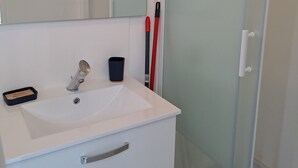 A bathroom with a white sink, mirror, and glass shower enclosure. - LOVELY, FULLY-EQUIPPED STUDIO WITH TERRACE 5 MINUTES' DRIVE FROM THE BEACH (Fouesnant)