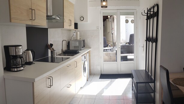 A modern kitchen with a central island, a sink, and a dining area with a bench. - LOVELY, FULLY-EQUIPPED STUDIO WITH TERRACE 5 MINUTES' DRIVE FROM THE BEACH (Fouesnant)