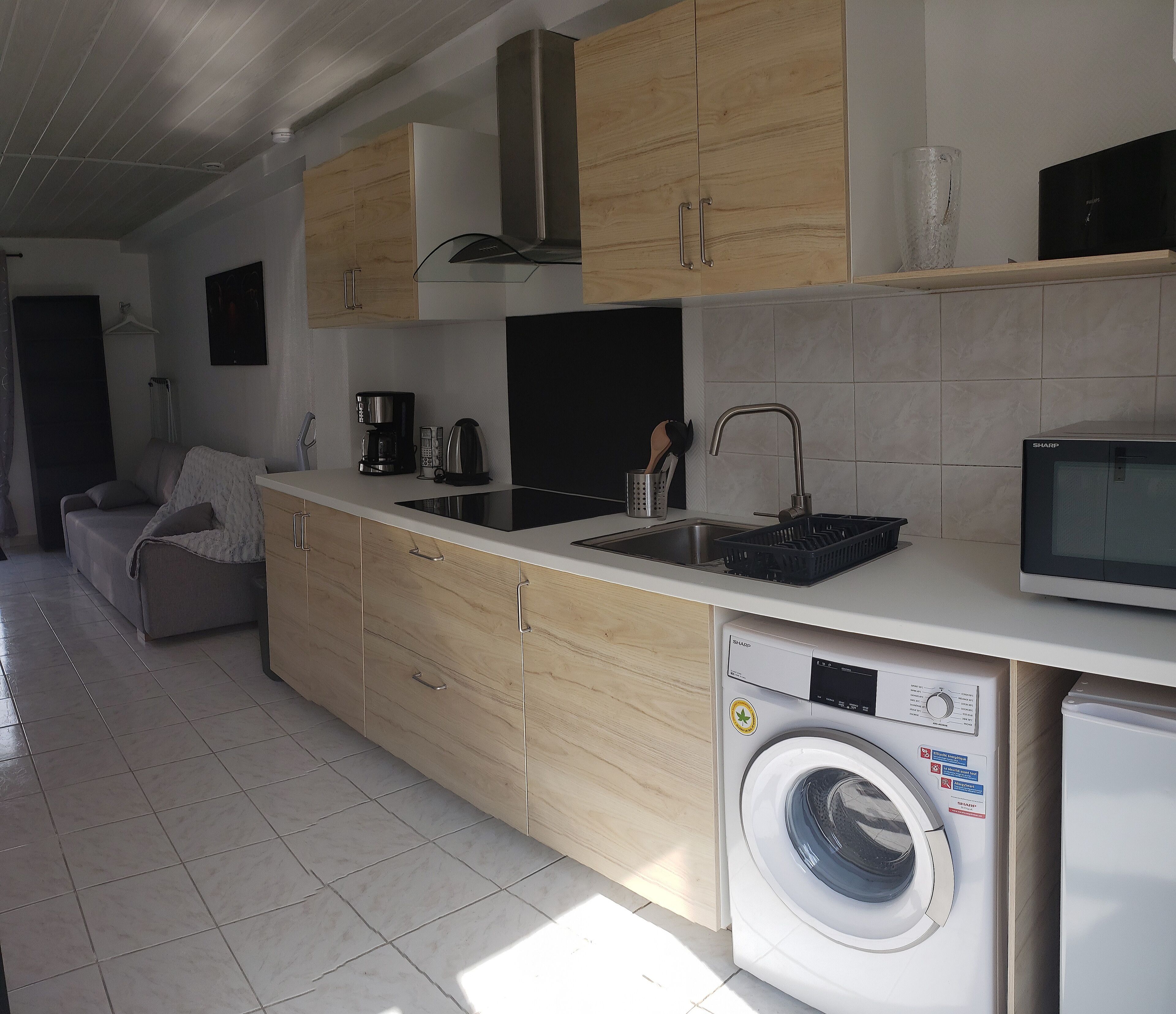 A modern kitchen with a built-in washing machine, a coffee maker, and a microwave.