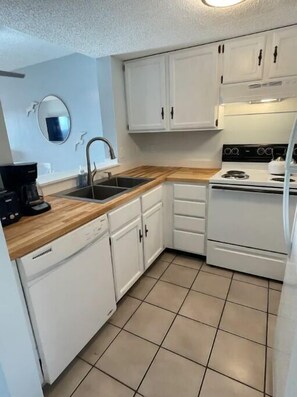 Kitchen features a sink, dishwasher, stove with oven, and tile flooring.