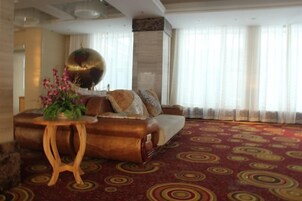 A room with a patterned carpet, a sofa set, a round table with flowers, and a large decorative globe.