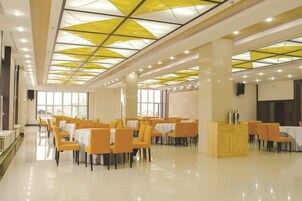 Un comedor amplio con mesas y sillas, un techo alto con patrones geométricos y ventanas grandes que dejan entrar luz natural.