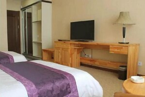 Una habitación de hotel con una cama, un escritorio de madera con un televisor, una lámpara y una mesita.
