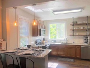 Kitchen features a central island with a sink and stove, along with wooden cabinets and a microwave.