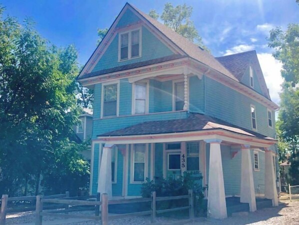 Situated in a serene tree-lined area, this charming two-story building features a gabled roof and a welcoming front porch.