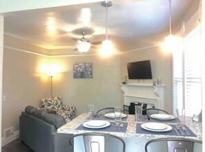 Enjoy meals with family and friends at this dining area, featuring a table for four, a fireplace, and a mounted TV.