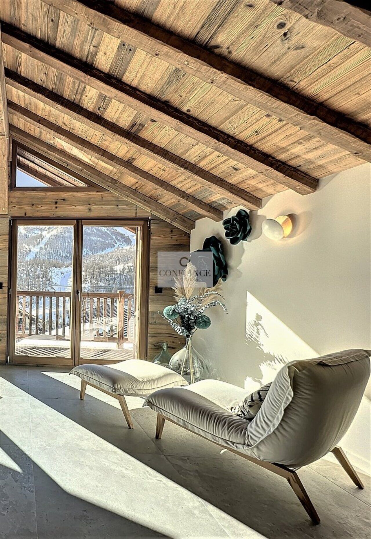 Ein modernes Interieur mit Holzboden, einer Couch und Blick auf eine verschneite Berglandschaft durch eine Glastür.
