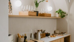 Una encimera de cocina con detalles de madera, una superficie de trabajo blanca y varios utensilios como una tostadora, pan y una tabla de cortar.