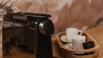 A coffee machine on a wooden table with a cup and saucer and a tray with more cups and a small item.