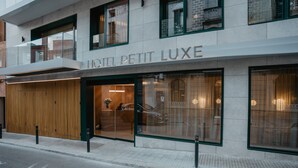 Fachada de hotel con una entrada amplia, un mostrador de recepción y un coche estacionado afuera.