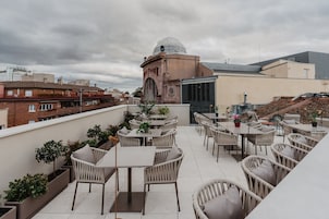 Terraza en la azotea con mobiliario exterior y vistas a la ciudad.